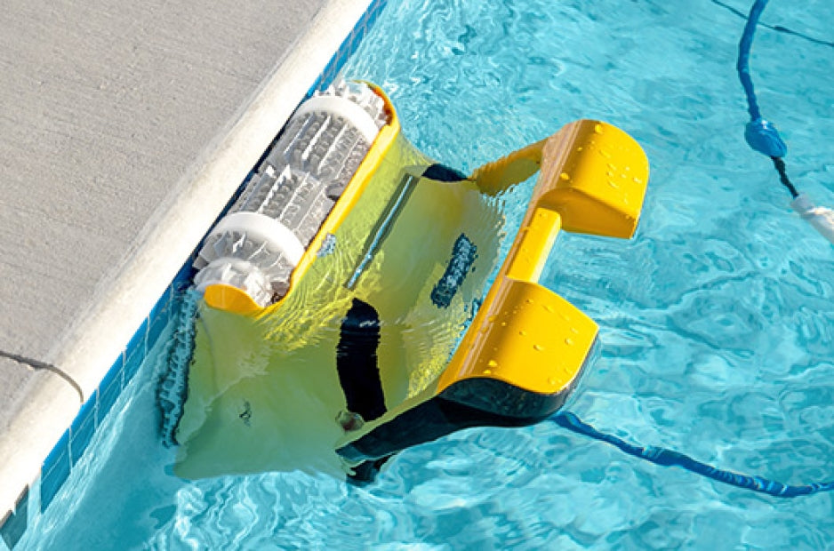 Robot piscina Dolphin PRO X1 giallo in azione sul fondo, vicino al bordo piscina.