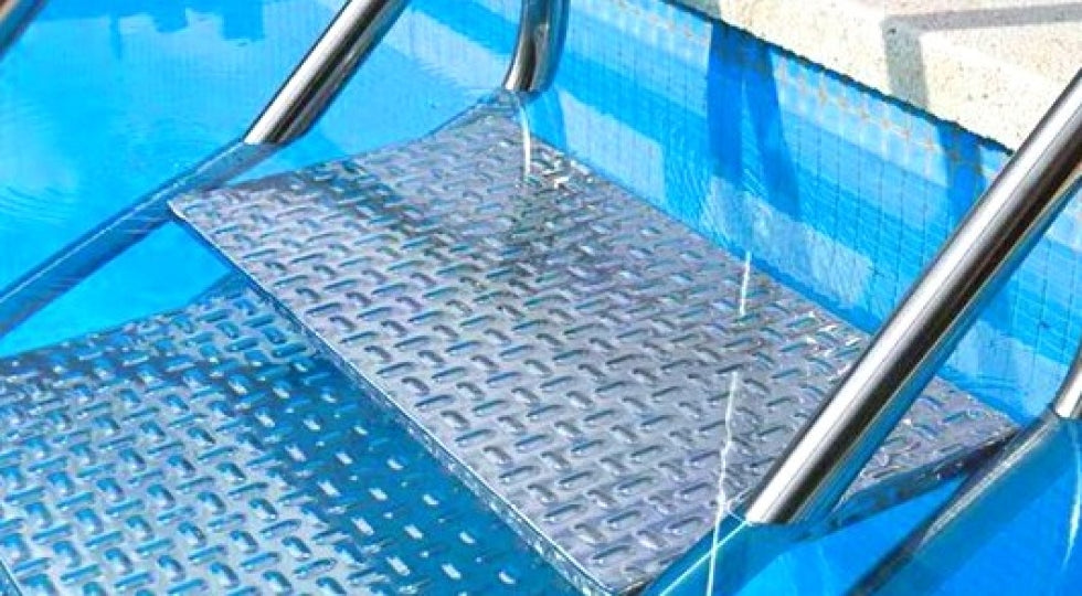 Scaletta piscina in acciaio inox AISI 316, accesso facilitato, immersa in acqua blu.