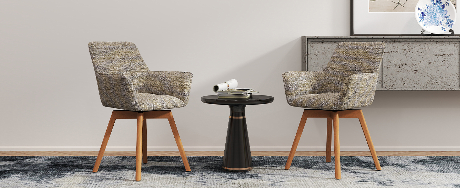 Deux chaises d'appoint rembourrées beiges avec pieds en bois positionnées autour d'une petite table d'appoint ronde noire contre un mur gris clair.