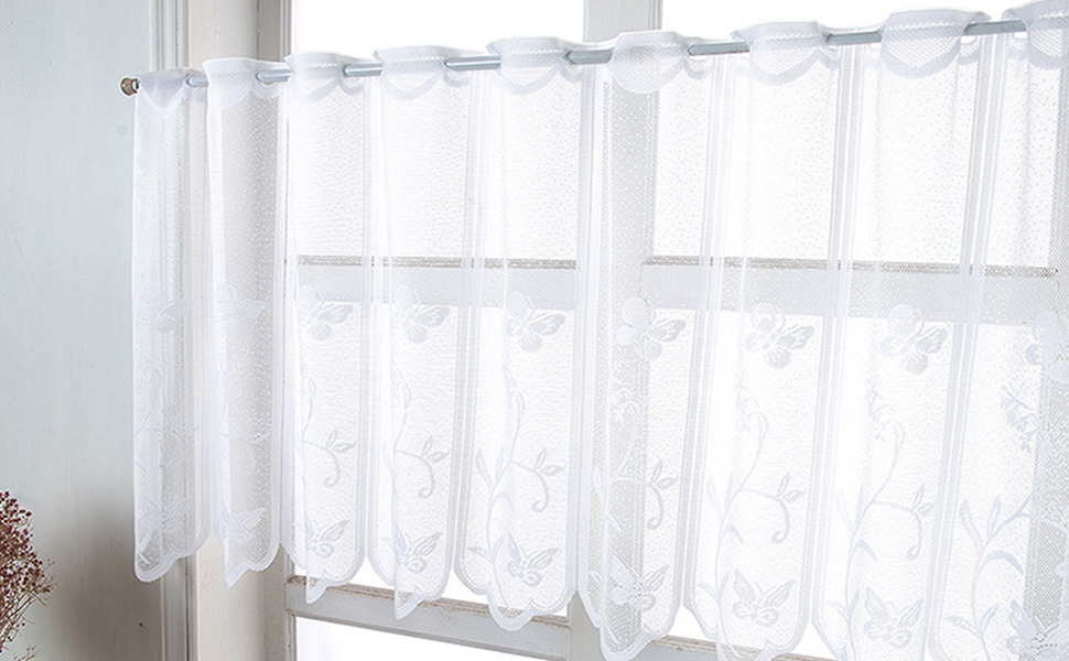 Rideaux de café transparents blancs suspendus à une tringle à rideau. Les rideaux ont un aspect délicat et translucide et recouvrent la moitié inférieure d'une fenêtre.