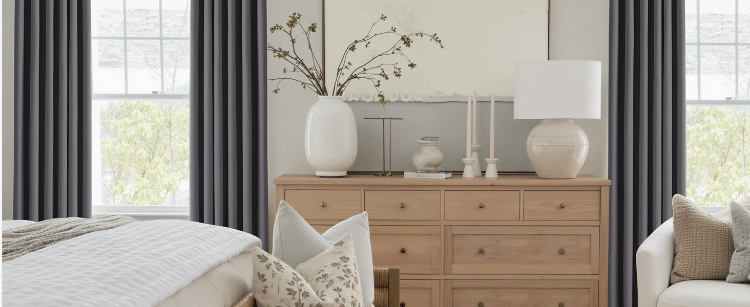 Intérieur lumineux du salon avec commode en bois naturel, rideaux blancs et vases décoratifs. Les grandes fenêtres fournissent un éclairage naturel.