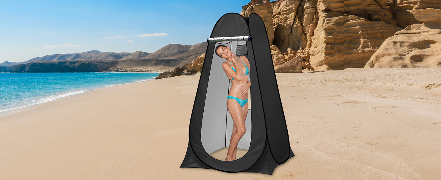 sur une plage de sable. La tente est ouverte, laissant apparaître une personne à l'intérieur. La toile de fond montre de l'eau bleue et des falaises rocheuses.