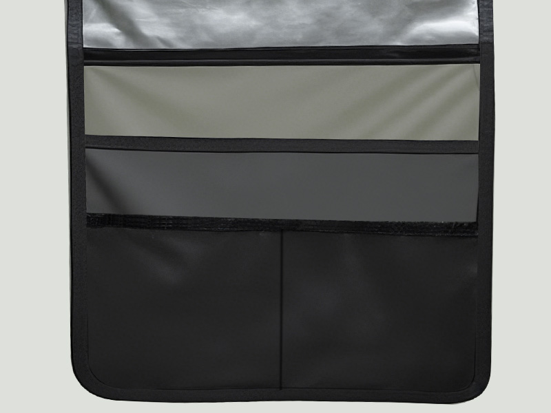 Organiseur en tissu à poches multiples avec quatre sections horizontales dans différentes nuances de gris et de noir. Les deux poches inférieures sont plus grandes et noires.