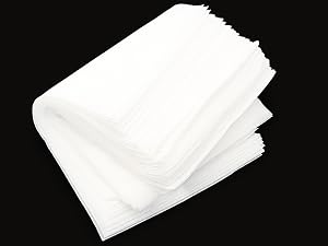 Pile de mouchoirs ou de serviettes en papier jetables blancs photographiés sur fond noir, montrant des bords superposés