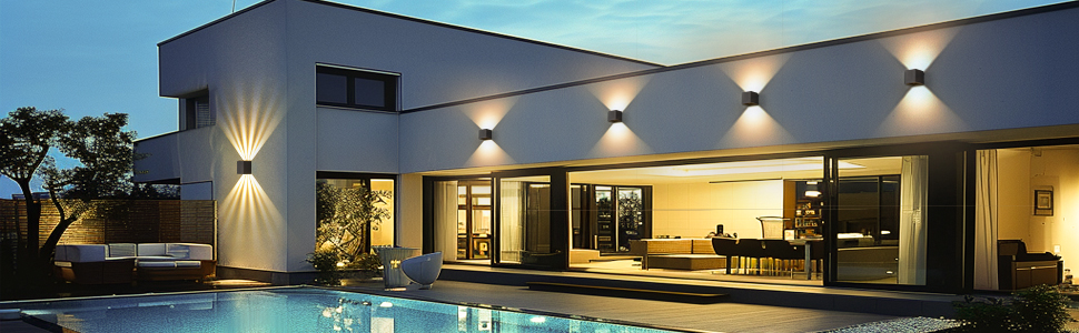 Extérieur d'une maison de luxe moderne la nuit avec une architecture géométrique, des appliques murales de haut en bas, de grandes fenêtres et un patio couvert