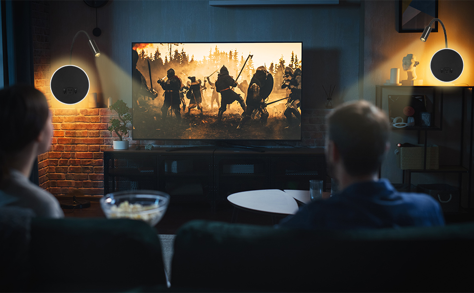 Configuración de entretenimiento doméstico con un televisor grande que muestra una escena de acción, rodeado de iluminación ambiental en una habitación con poca luz y los espectadores en el sofá