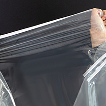 Gros plan des mains montrant l'ouverture ou la fermeture d'un sac de rangement en plastique transparent ou d'un matériau d'emballage