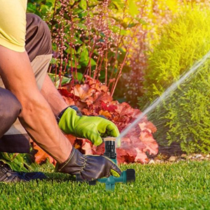 un homme arrose un jardin avec un tuyau