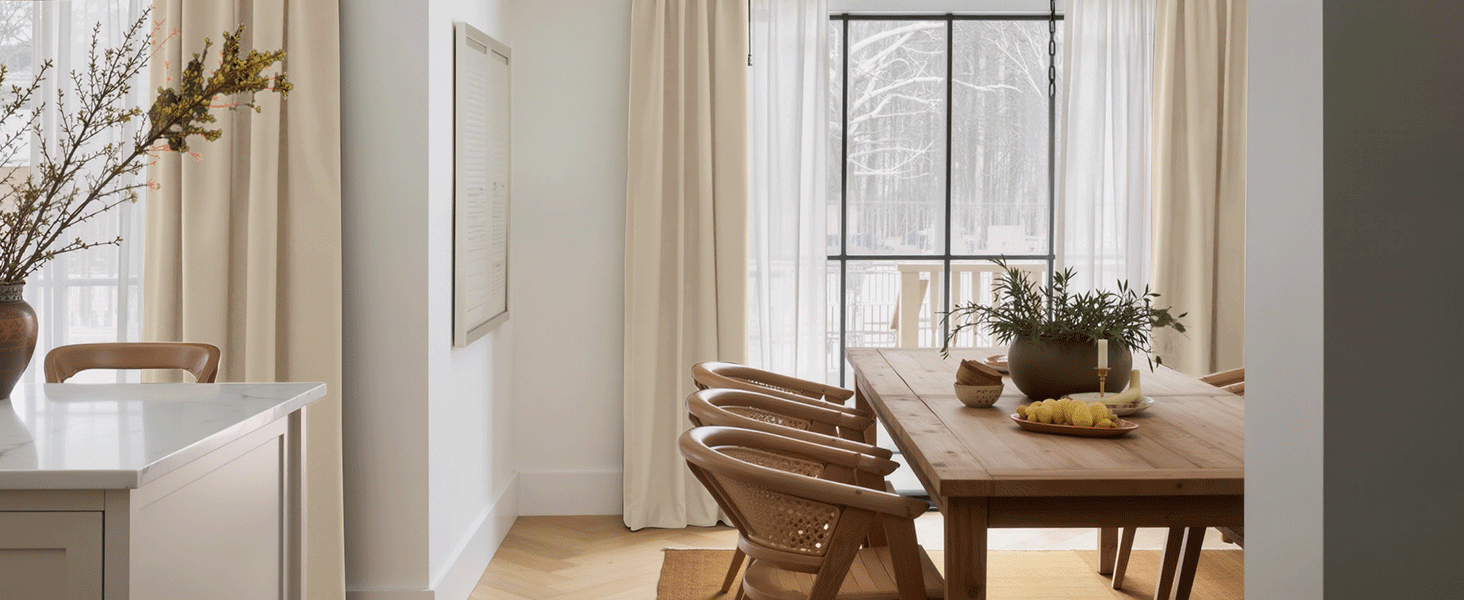 Aménagement intérieur de la pièce montrant une salle à manger avec une table en bois, des chaises et une fenêtre avec rideaux.