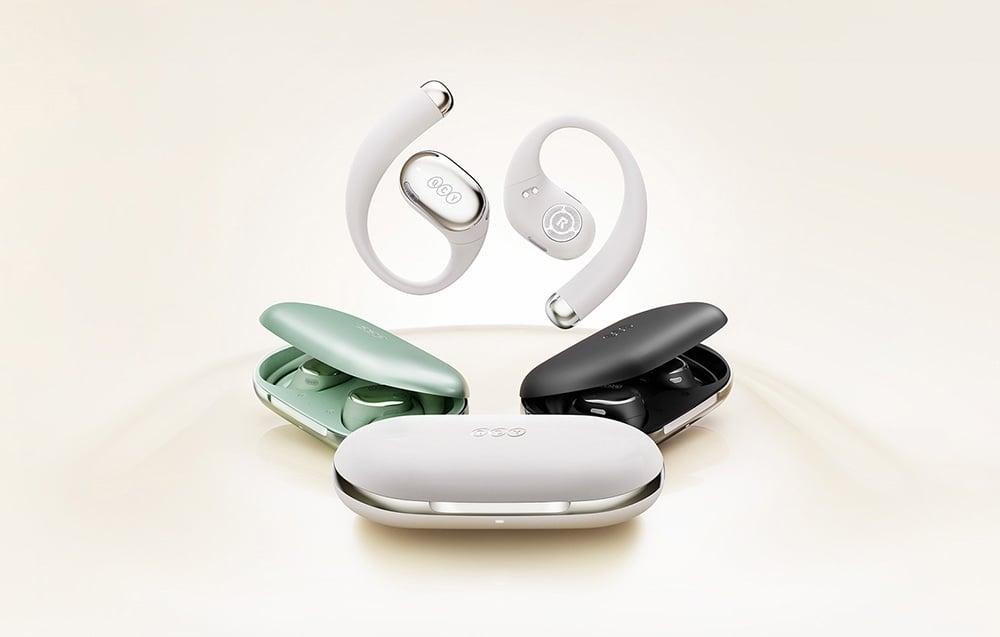 Cuffie wireless bianche con ganci auricolari che fluttuano sopra tre custodie di ricarica colorate: verde, nera e bianca.
