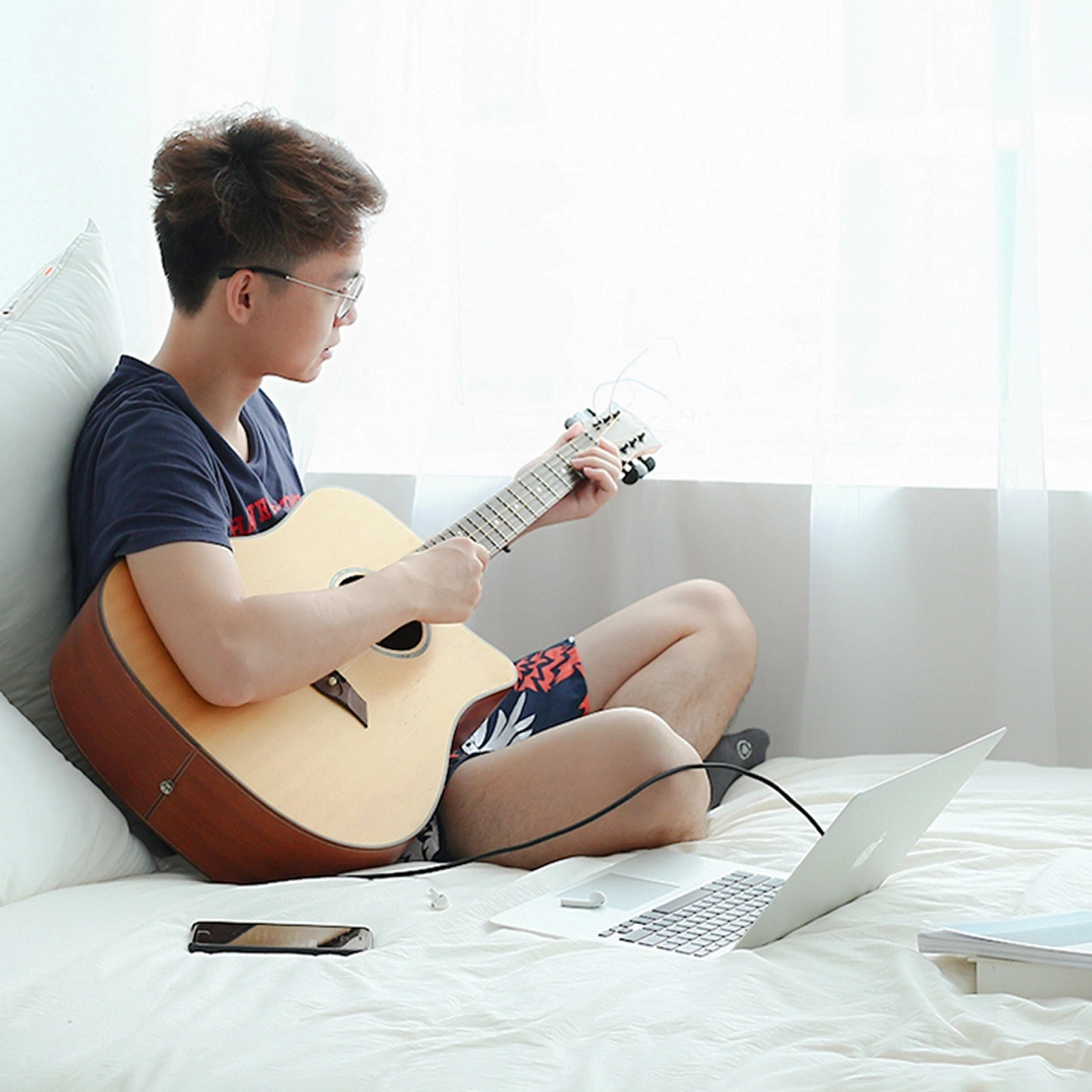 Uomo suona la chitarra collegata al computer utilizzando il cavo audio TRS Ugreen AV127