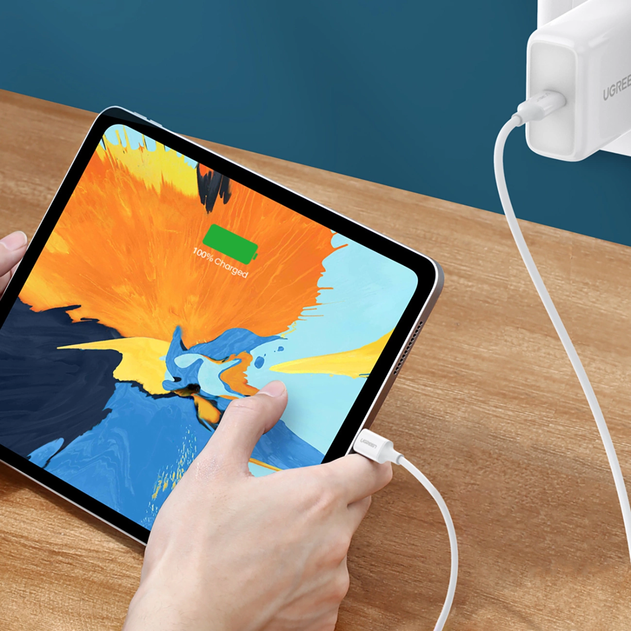 Tableta conectada a una toma de corriente con un cable Ugreen US264