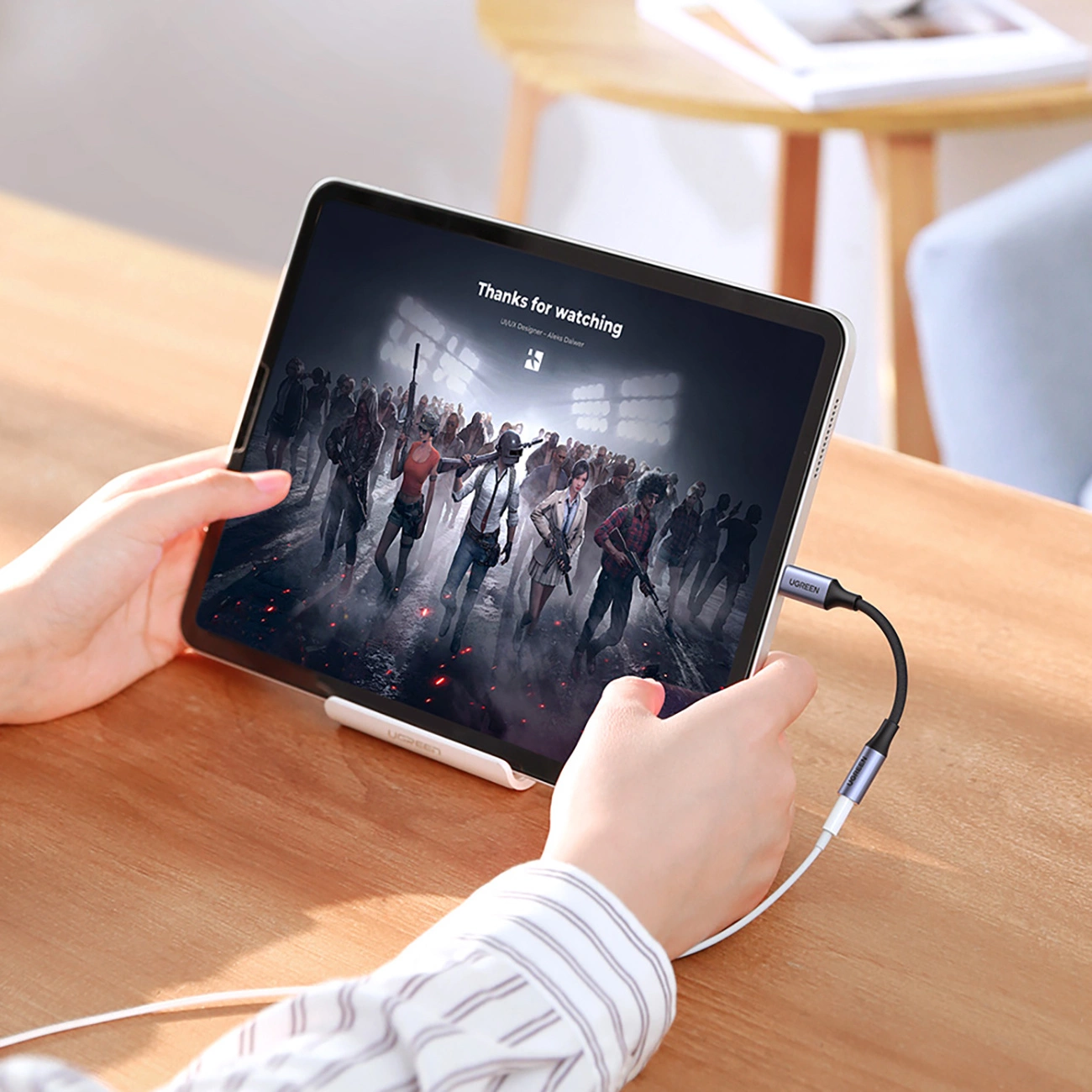 Personne regardant un film sur une tablette connectée à l'adaptateur audio Ugreen AV161 pour écouteurs