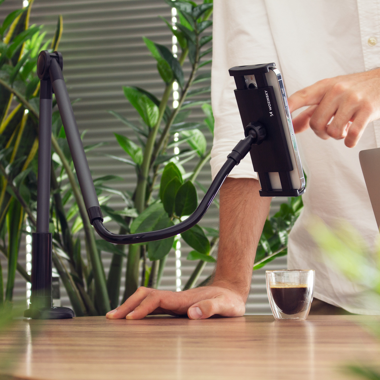 El modelo muestra una tableta en el soporte flexible Wozinsky WTHBK5 montado sobre una mesa