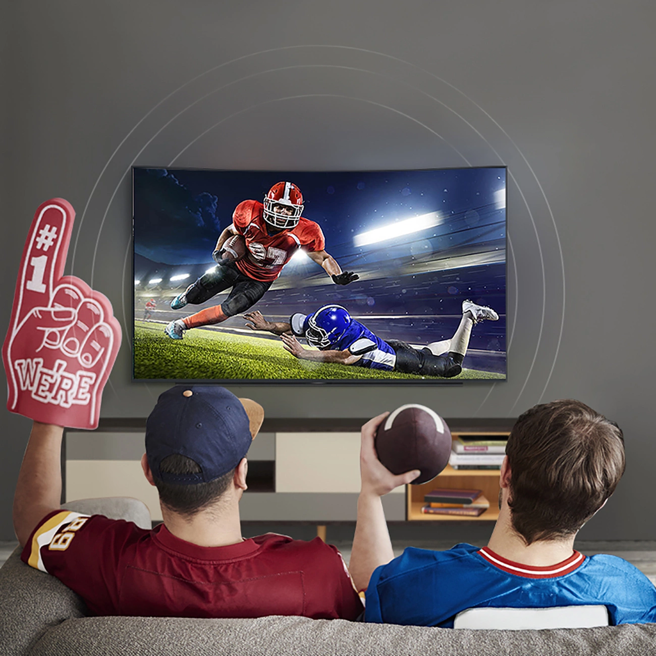 Dos hombres están viendo fútbol americano en un televisor conectado al cine en casa con el cable óptico Ugreen AV122