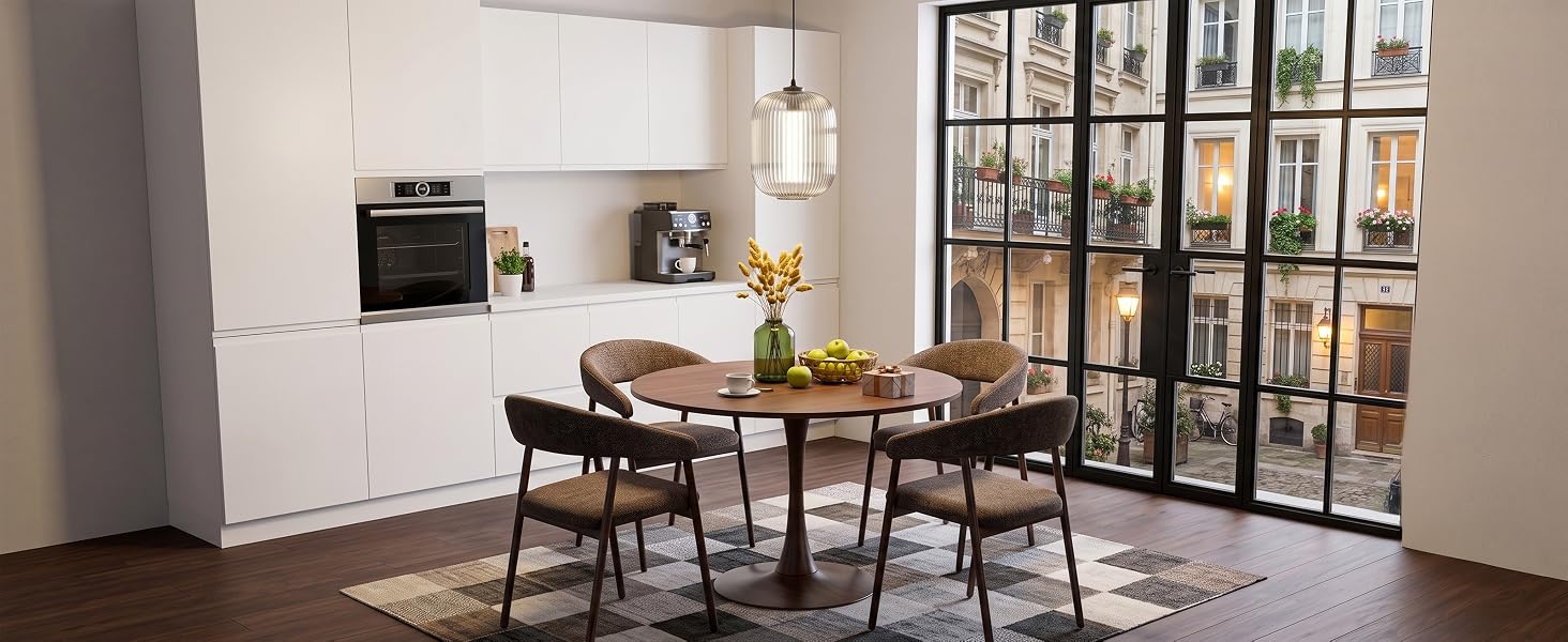 Salle intérieure moderne présentant une table à manger avec des chaises noires, une étagère murale avec des livres et des objets de décoration, une esthétique minimaliste avec des murs blancs, un éclairage chaleureux et un mobilier de maison contemporain.
