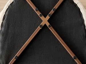 Gros plan de la surface du tissu noir avec deux lanières en cuir beige/beige croisées en forme de X, montrant la texture et les détails du tissage.