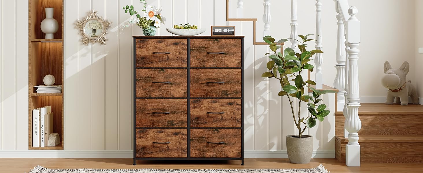 Commode en bois à huit tiroirs, finition rustique. Structure en métal, style industriel. Placé dans une chambre avec des murs blancs, des plantes décoratives et des étagères