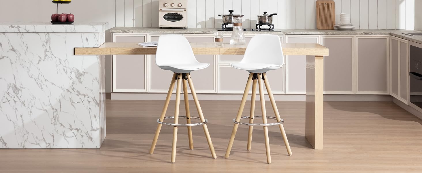 Cocina moderna con isla de mármol, barra de desayuno de madera y dos taburetes altos blancos con patas de madera. Electrodomésticos y decoración visibles en segundo plano