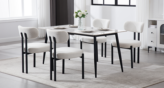Moderne Essgruppe mit rechteckigem weißem Tisch und vier weißen gepolsterten Stühlen mit schwarzen Metallrahmen. Es befindet sich in einem hellen Raum mit weißem Dekor