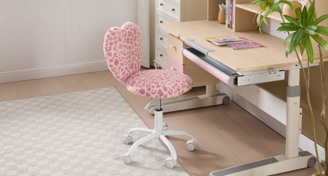 Pink heart-patterned desk chair shown against white desk and light-colored carpet in home office setting.