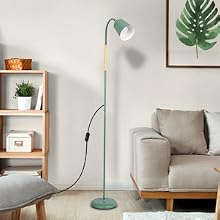 Mintgrüne Stehlampe mit verstellbarem Kopf neben einem grauen Sofa in einem minimalistischen Wohnzimmer mit Holzregalen und tropischer Wandkunst