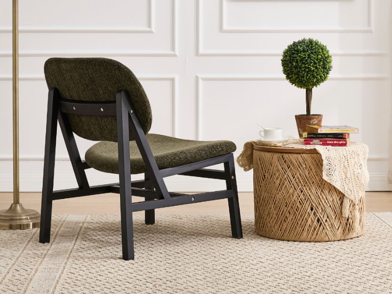 Chaises noires modernes à profil bas avec sièges tissés, présentées dans le salon avec des plantes décoratives et un panier tressé sur un tapis à motifs clairs.