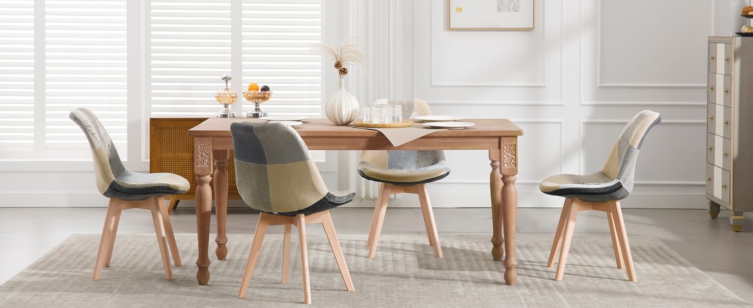 Tavolo da pranzo in legno con quattro sedie moderne. Il tavolo ha una finitura rustica, le sedie presentano rivestimento grigio e gambe in legno. La camera ha pareti bianche e persiane.