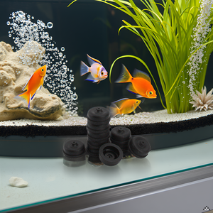Aquarium with colorful fish, plants, and bubbles. Black rubber suction cups in foreground, likely for securing aquarium equipment or decorations.