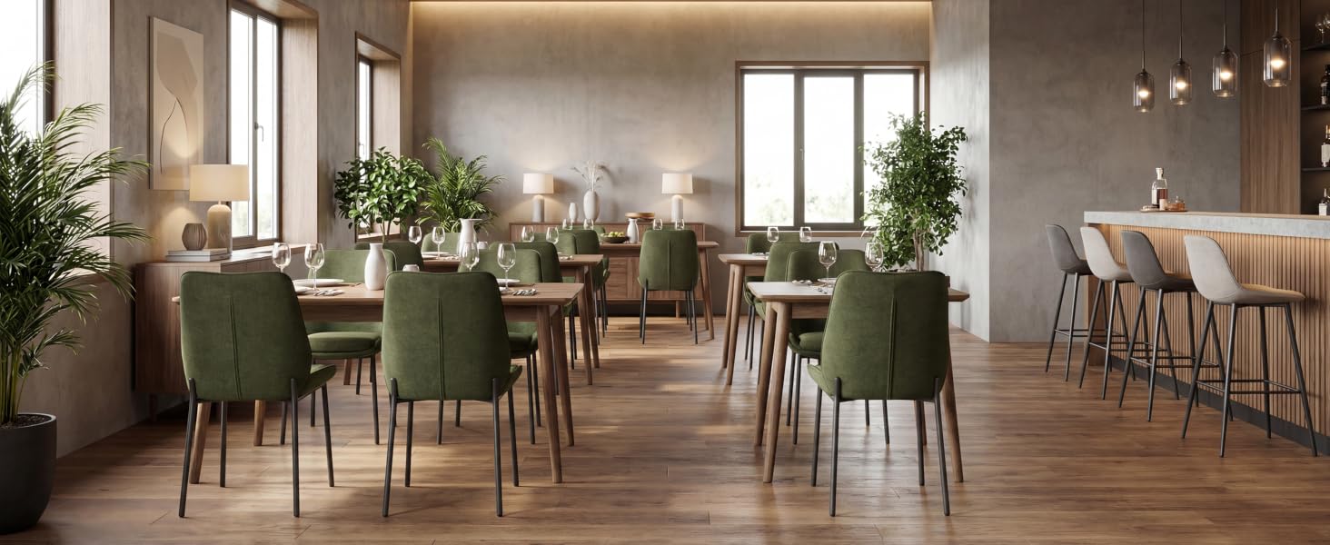 Modernes Esszimmerinterieur mit beigen Wänden, modernem Esstisch aus Holz, gepolsterten Stühlen in Salbeigrün, Pendelleuchten, Topfpflanzen und raumhohen Fenstern mit hellem Tageslicht.