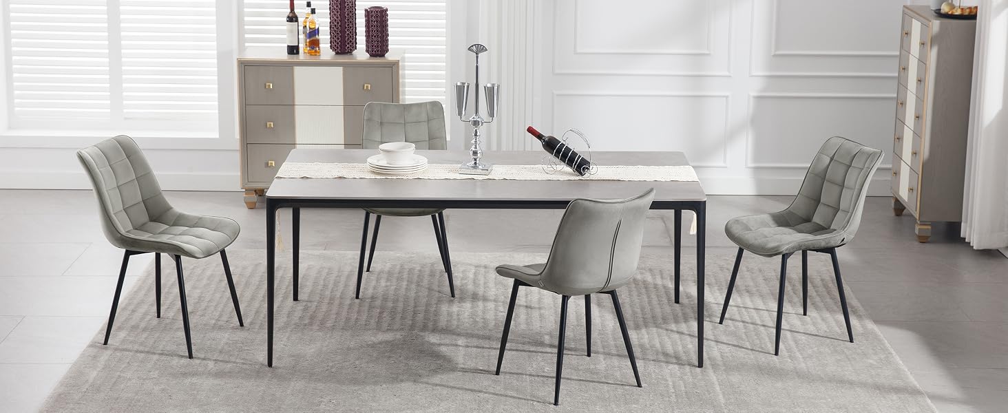 Modern dining set with rectangular marble-top table and four gray upholstered chairs featuring metal legs, arranged in a minimalist white room.