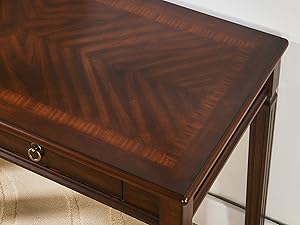 Table d'appoint en bois avec une finition riche et foncée. Comprend un tiroir unique avec poignée annulaire en laiton. Le dessus de table présente un motif de grain de bois à chevrons distinctif