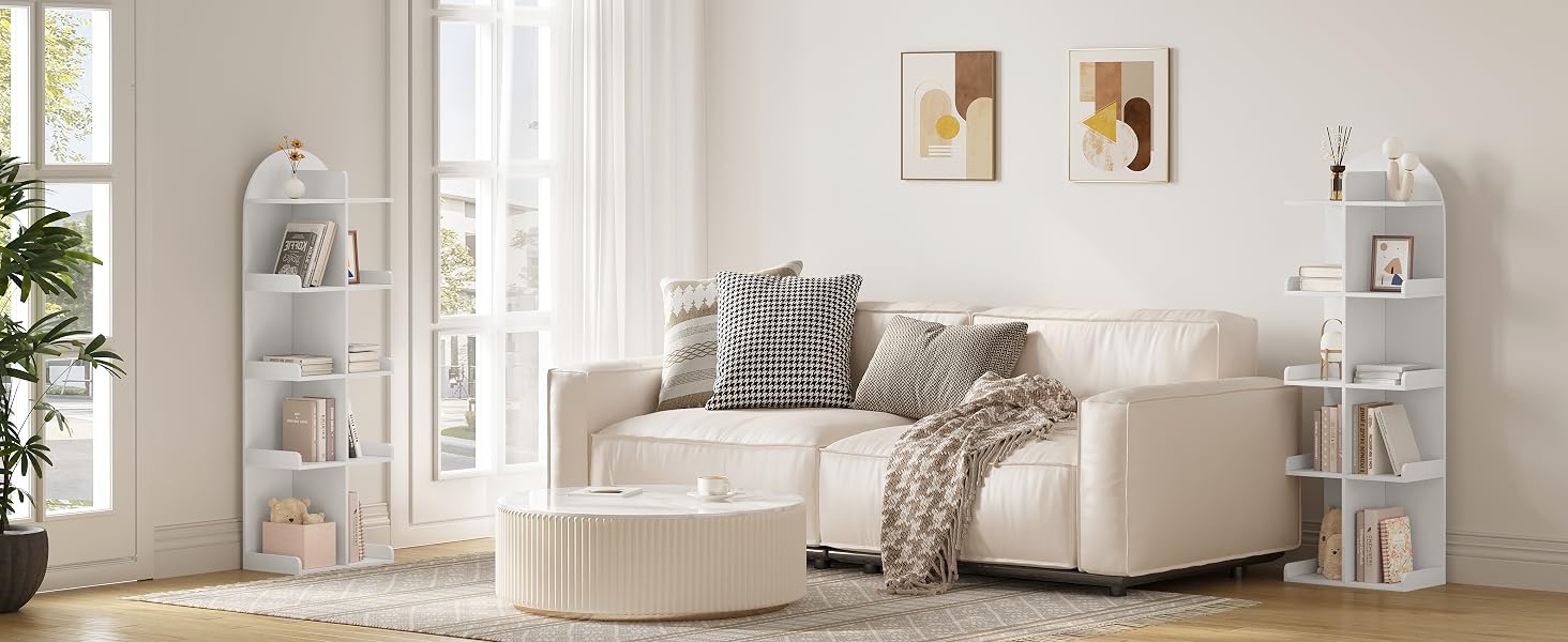 Accogliente soggiorno con divano componibile curvo color crema, pouf rotondo e scaffali angolari bianchi abbinati che espongono