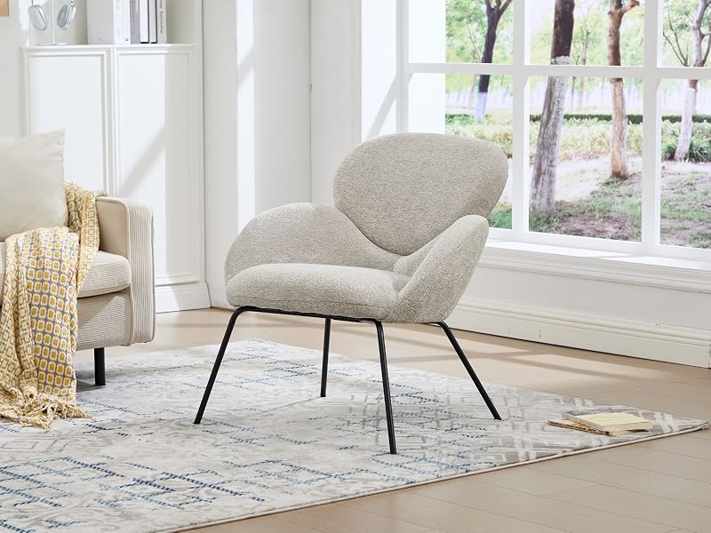 Interno del soggiorno moderno e minimalista con poltrone imbottite grigio chiaro e divano appoggiati su pareti bianche e ampie finestre, con luce naturale che entra.