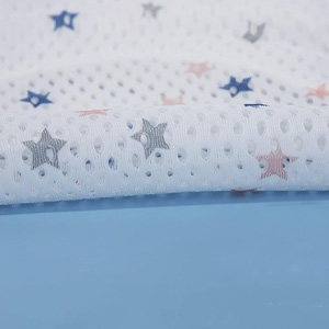 Gros plan sur un tissu blanc avec imprimé décoratif en forme d'étoile dans les couleurs bleu et rose sur fond bleu clair