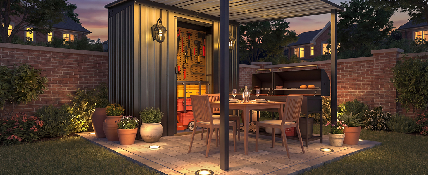 Outdoor garden patio at dusk with warm ambient lighting, featuring seating area, potted plants, and brick walls creating cozy evening atmosphere.