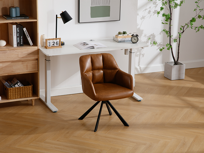 Bureau blanc à hauteur réglable, associé à une chaise pivotante en cuir marron. La configuration du bureau à domicile comprend une lampe de bureau, un calendrier et des objets décoratifs sur du parquet.
