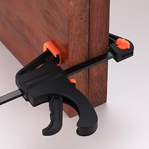 noire et orange saisissant une surface en bois, dotée d'une poignée à gâchette et d'un mécanisme coulissant réglable