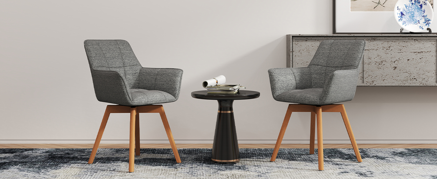 Deux chaises d'appoint rembourrées beiges avec pieds en bois positionnées autour d'une petite table d'appoint ronde noire contre un mur gris clair.