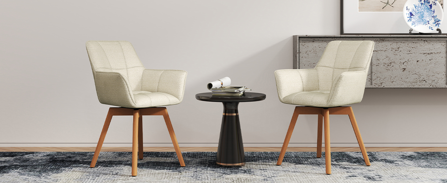 Deux chaises d'appoint rembourrées beiges avec pieds en bois positionnées autour d'une petite table d'appoint ronde noire contre un mur gris clair.