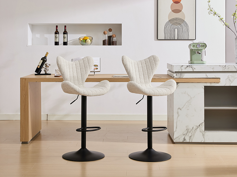 Moderna configurazione da cucina con due sgabelli da bar imbottiti color crema con basi in metallo nero. Arte murale e decorazioni minimaliste visibili sullo sfondo.