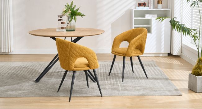 Set da pranzo moderno con tavolo rotondo in legno con gambe in metallo nero e due sedie imbottite giallo senape in un ambiente interno luminoso