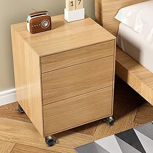 Light wooden storage unit or drawer system with wheels, shown in a home setting against light colored flooring and walls.