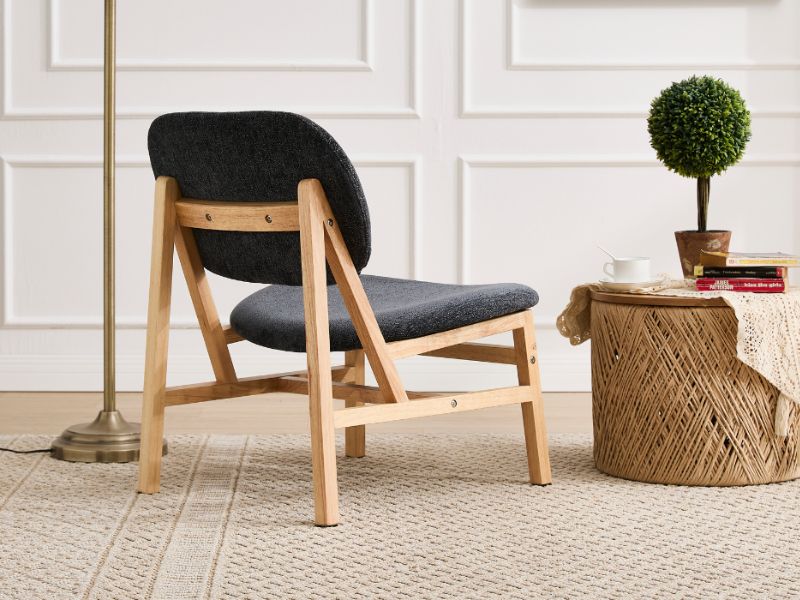 Cadre de salon moderne avec des chaises rembourrées noires minimalistes, des pieds en bois et des plantes topiaires décoratives en pot sur des murs lambrissés blancs.