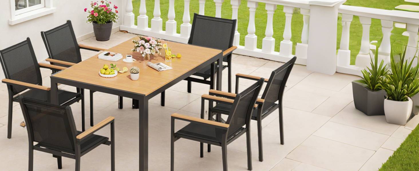 Outdoor patio dining set featuring wooden table with dark-framed chairs. Table set with dinnerware. White balustrade and potted plants visible in background.