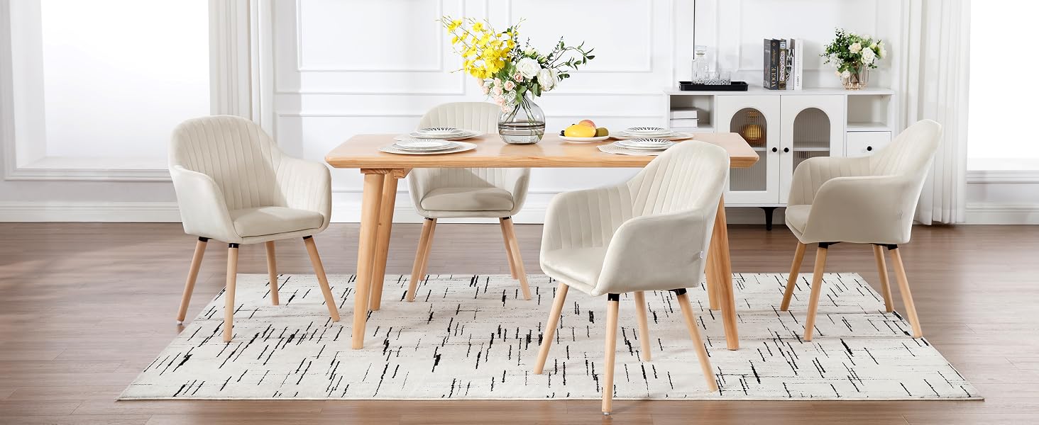 con mesa redonda de madera y cuatro sillas tapizadas de color crema sobre una alfombra con estampado geométrico
