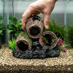 Step-by-step sequence showing placement of decorative log-shaped aquarium ornaments into gravel substrate with live plants visible.