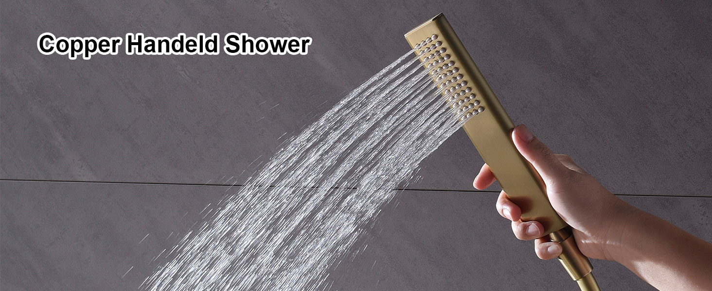 Pommeau de douche à main doré avec plusieurs buses de pulvérisation, illustré en train de pulvériser de l'eau sur un fond de carreaux gris. La main tenant le pommeau de douche est visible.