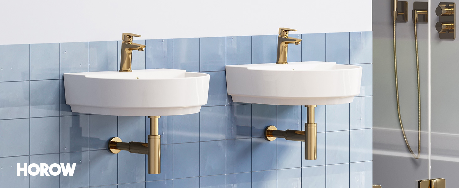 Due lavandini da bagno circolari bianchi montati su una parete piastrellata blu chiaro. Ogni lavandino ha un rubinetto dorato e un tubo di scarico visibili