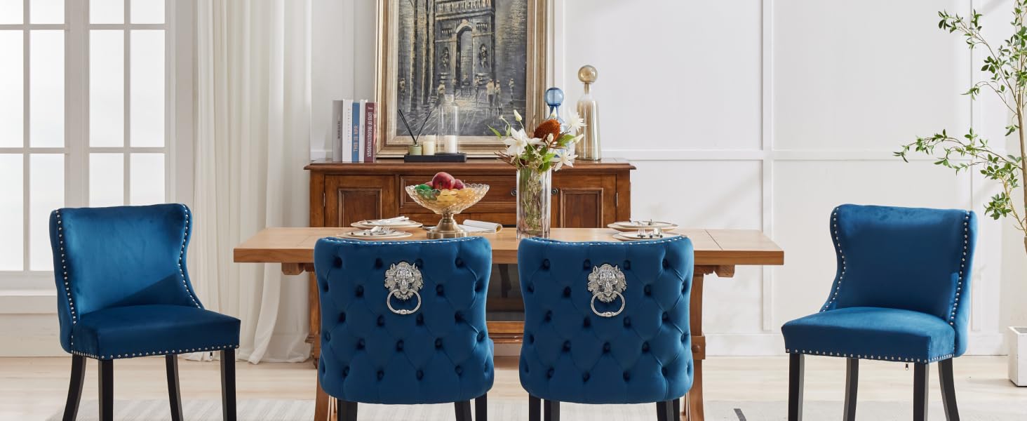 Juego de comedor con sillas tapizadas de terciopelo azul con respaldos acolchados y anillos decorativos de metal, dispuestas alrededor de una mesa de comedor de madera.